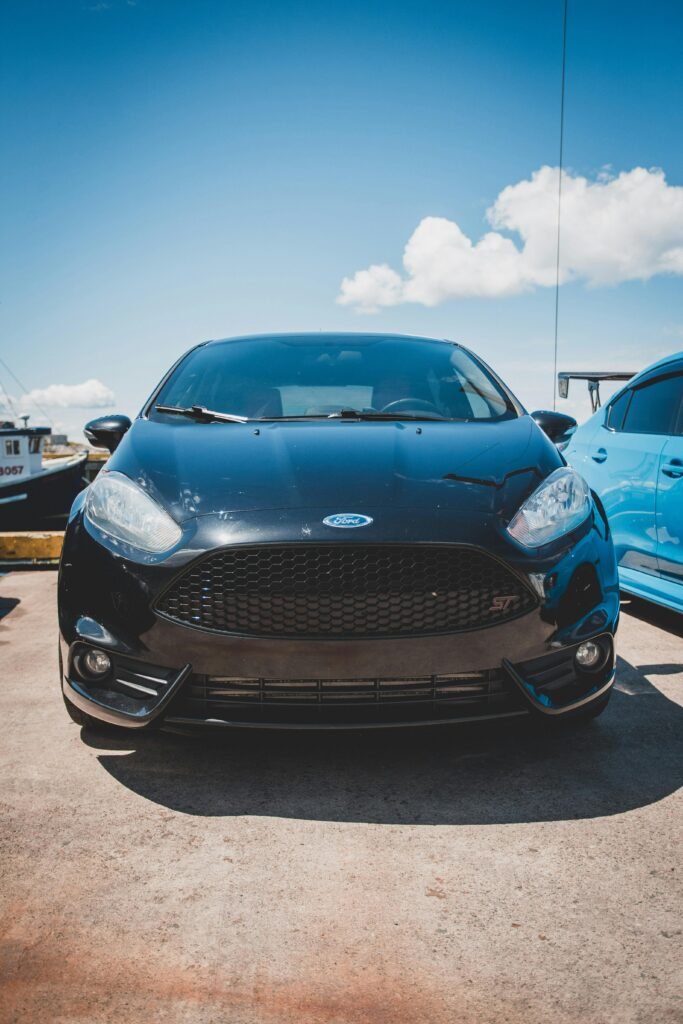 Front view of a classic black Ford Fiesta parked outdoors on a sunny day with a clear blue sky.