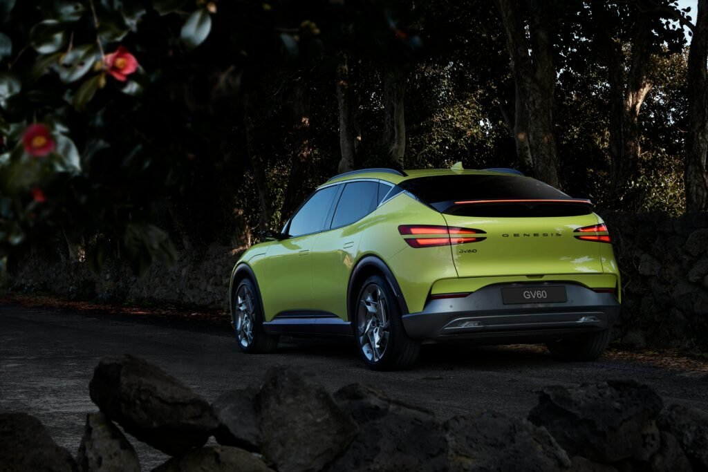 Capture of a luxury Genesis GV60 electric car parked on a winding road surrounded by nature.