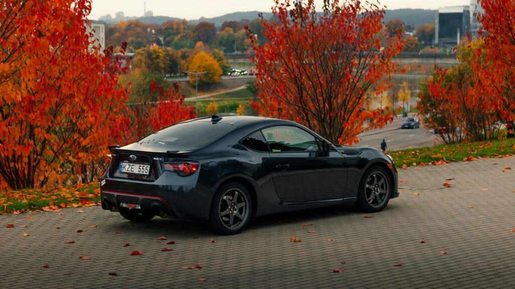 A shiny black Subaru BRZ parked amidst vibrant autumn foliage, showcasing fall beauty.