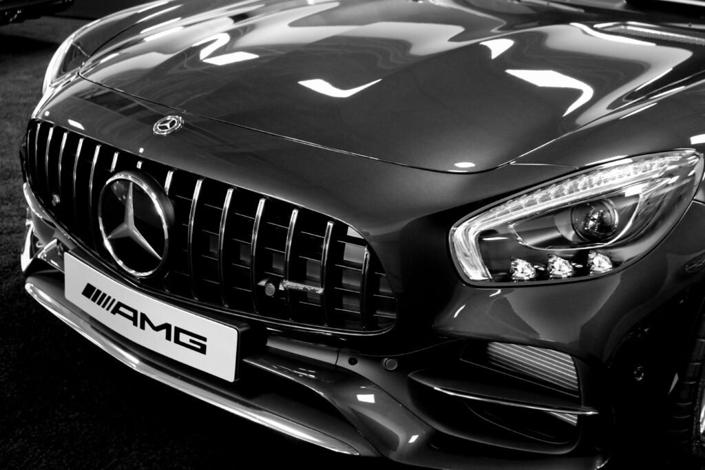 Detailed black and white photo of a luxury car's front grille and headlights, showcasing elegance and style.